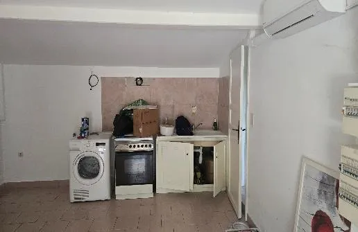 Cuisine avec lave-linge, cuisinière et meuble sous évier aux portes ouvertes