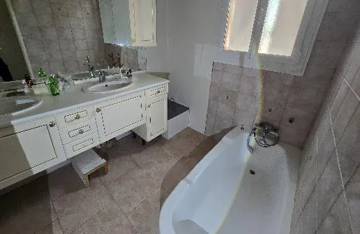 Salle de bain avec baignoire blanche, meuble double vasque et carrelage beige